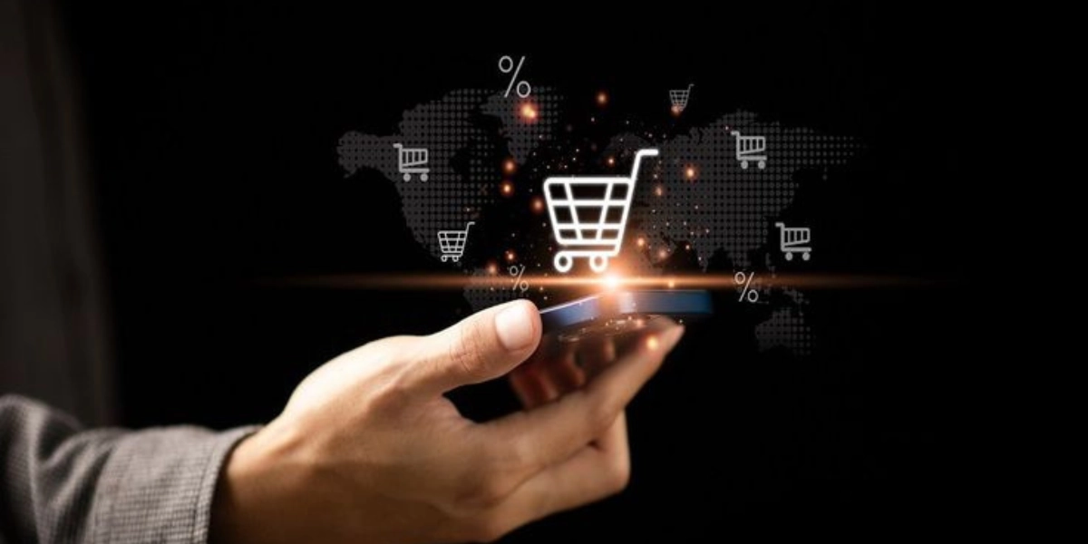 Hand holding a smartphone with a digital shopping cart icon representing e-commerce marketing and online shopping solutions